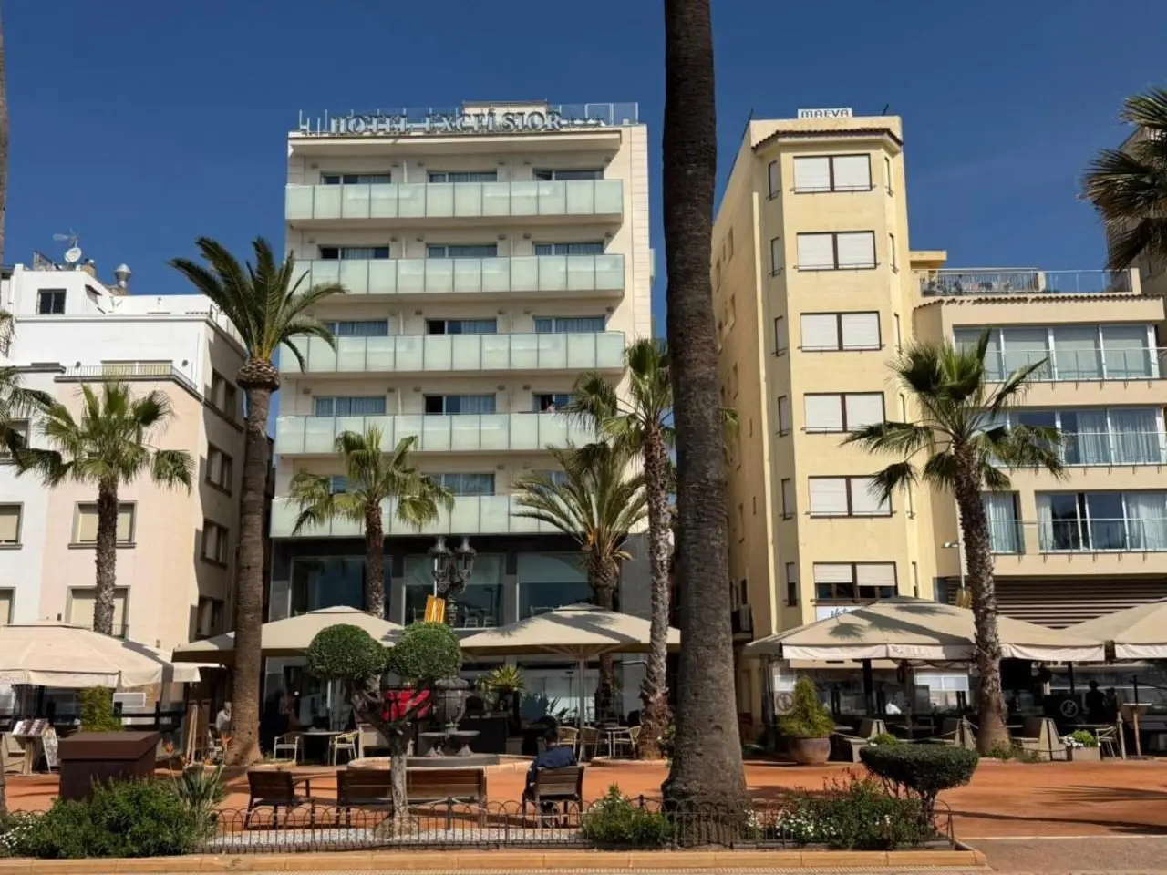 Fachada del Hotel Excelsior vista desde el paseo bordeado de palmeras