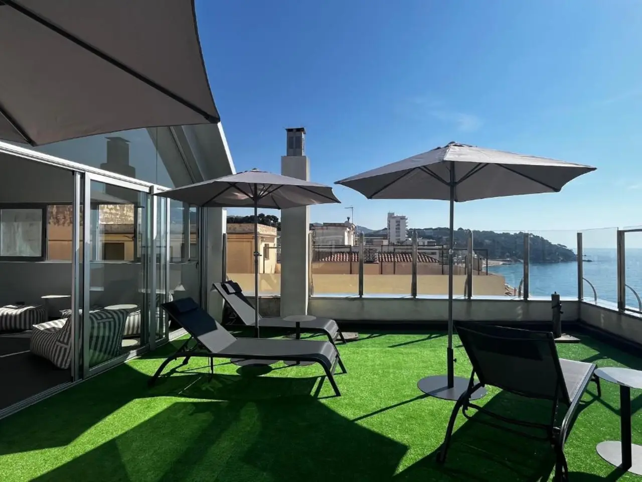 Terraza en la azotea con hamacas, sombrillas y vistas al mar